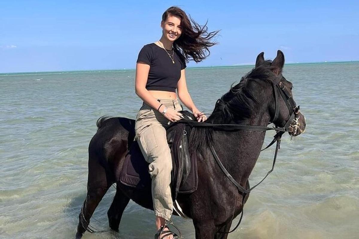 žena jedoucí na koni v oceánu