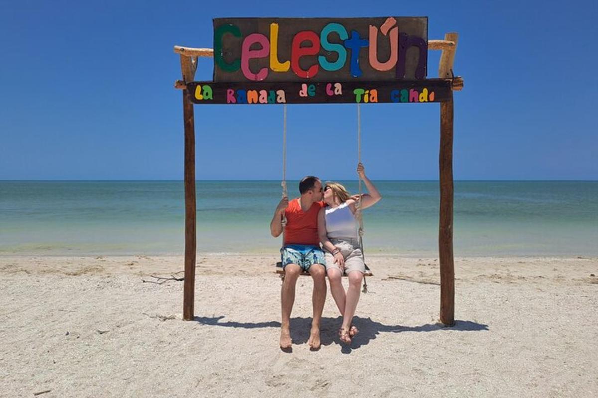 dua orang duduk di atas buaian di pantai