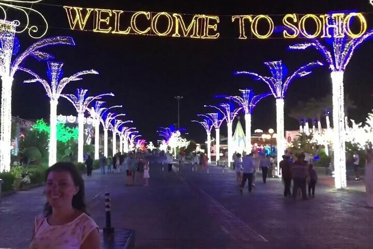 a woman standing in front of a street with christmas lights