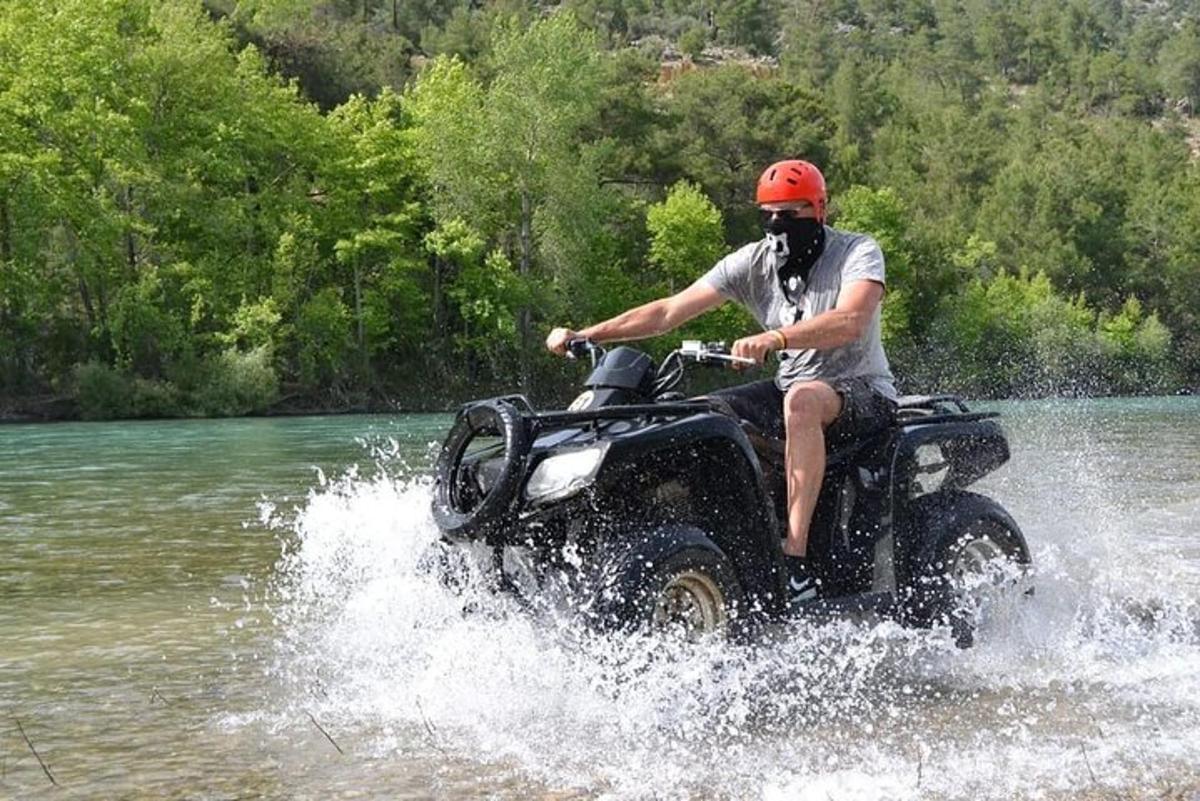 un uomo che guida un quad attraverso un fiume