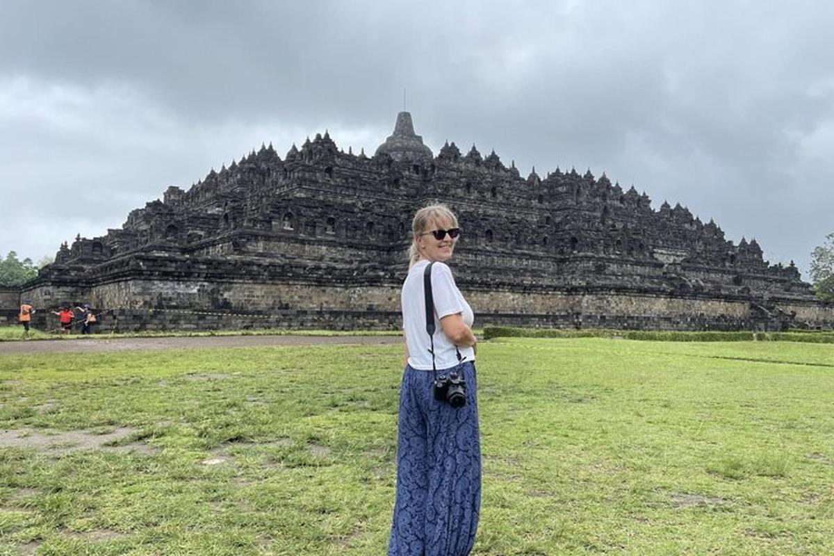 a woman standing in a field in front of a temple