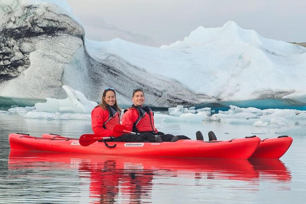 a man and woman in a red kayak in front of an iceberg