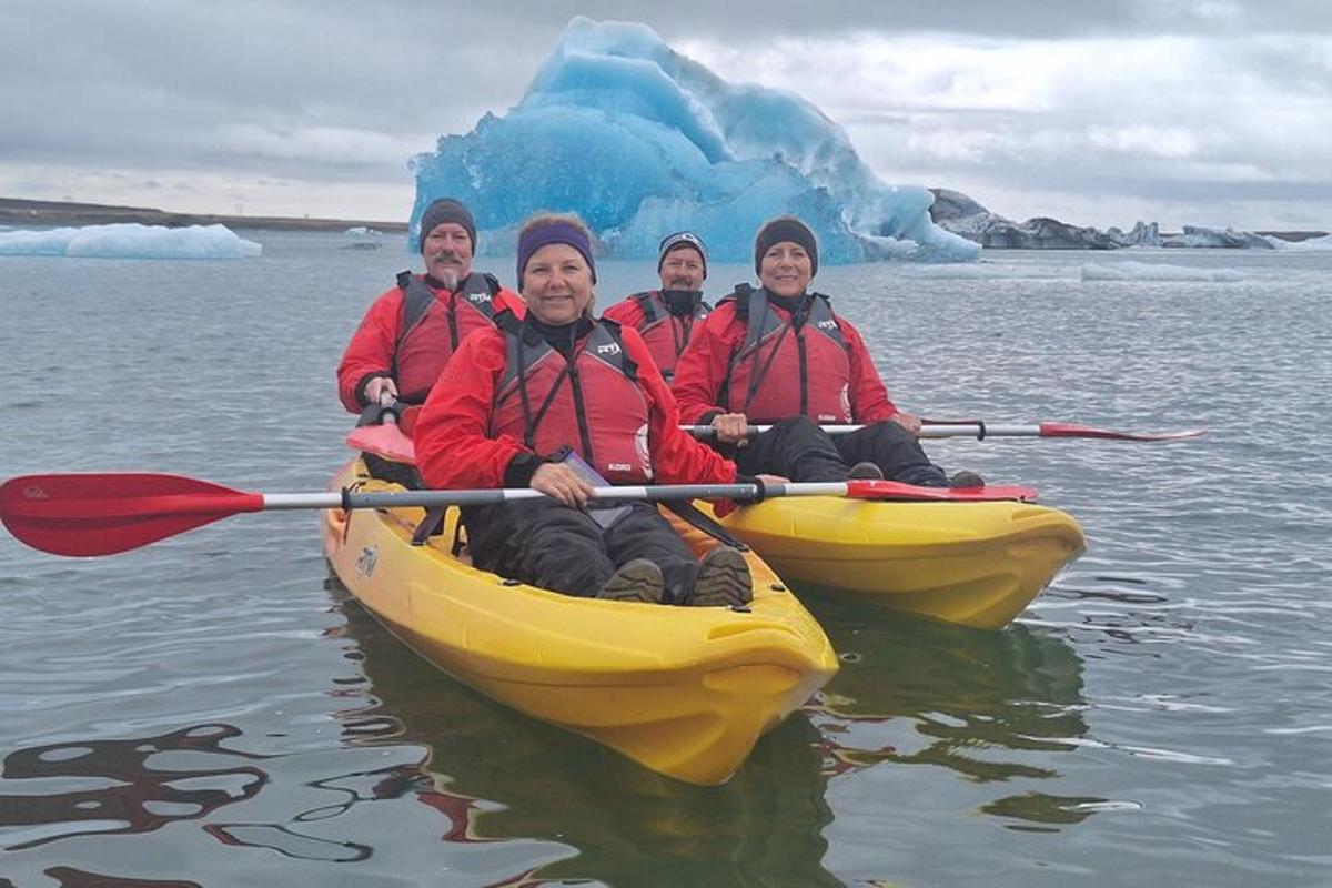a group of people in kayaks on the water with an iceberg