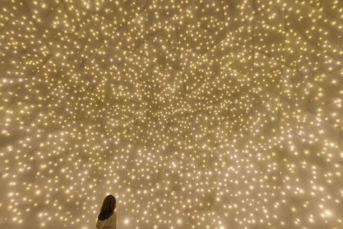 a woman standing in front of a wall with lights