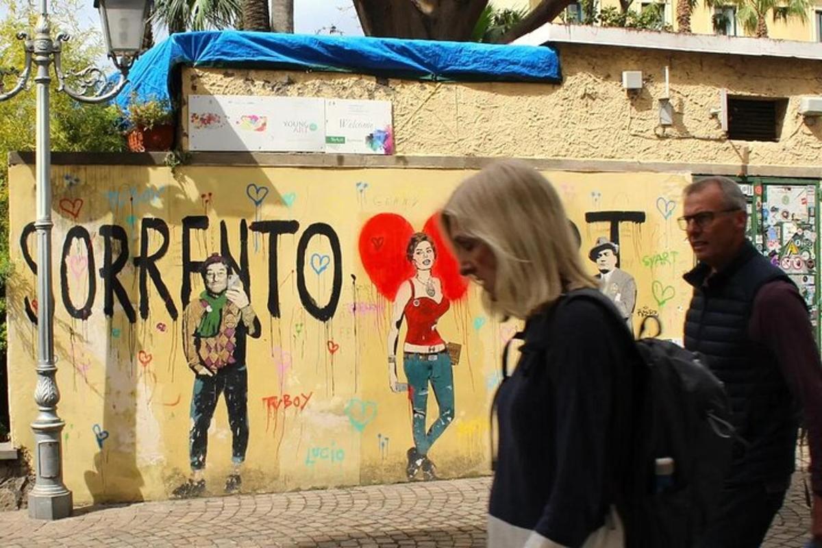 skupina lidí jdoucích před zdí s graffiti