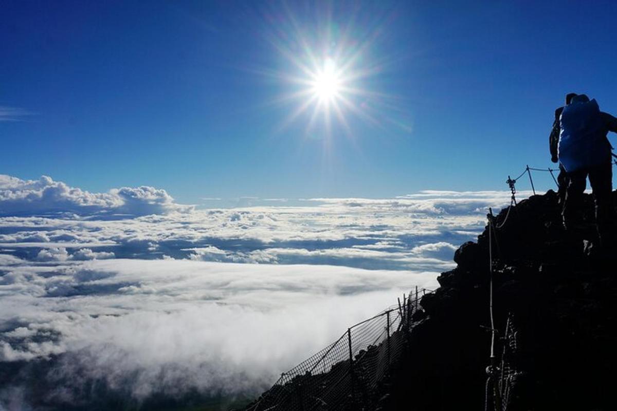 una persona in piedi sulla cima di una montagna che guarda oltre le nuvole