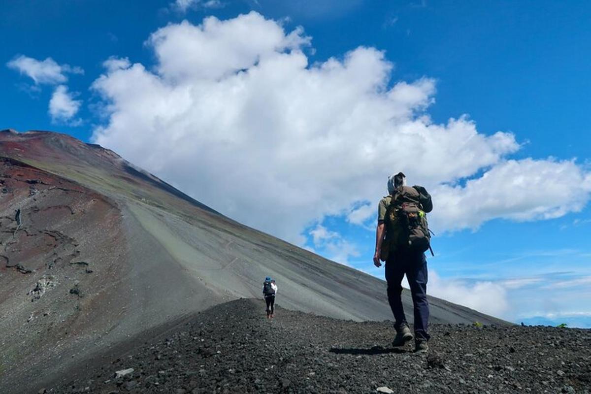 seseorang dengan beg galas berjalan mendaki gunung