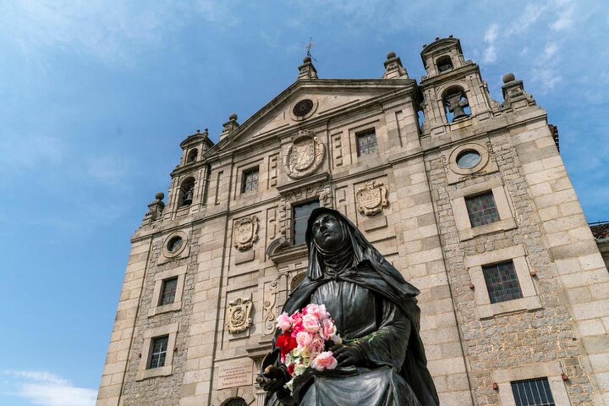 Una estatua de una mujer sosteniendo flores frente a un edificio.