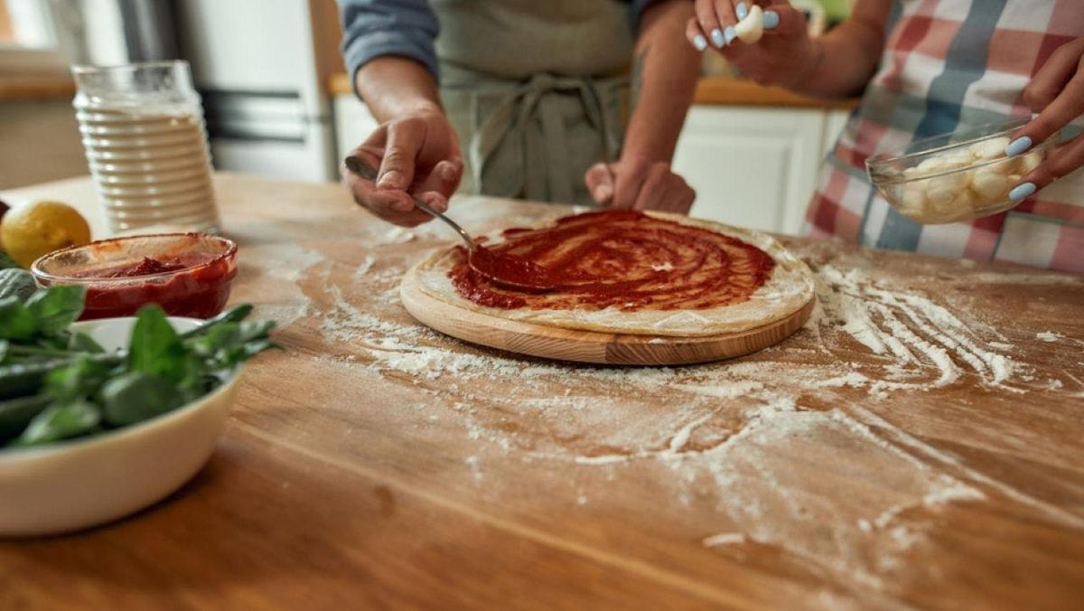 a person making a pizza on a wooden table