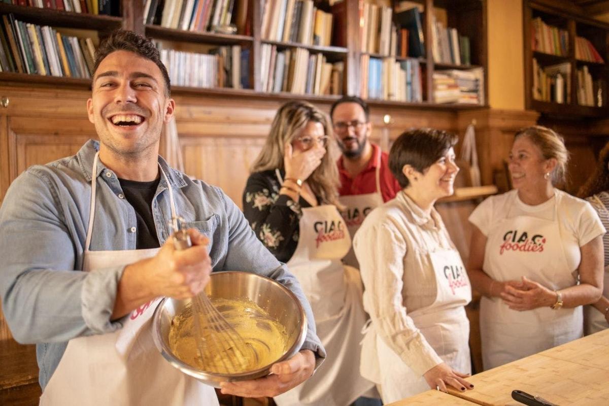 een groep mensen in een keuken met een man die een kom vasthoudt