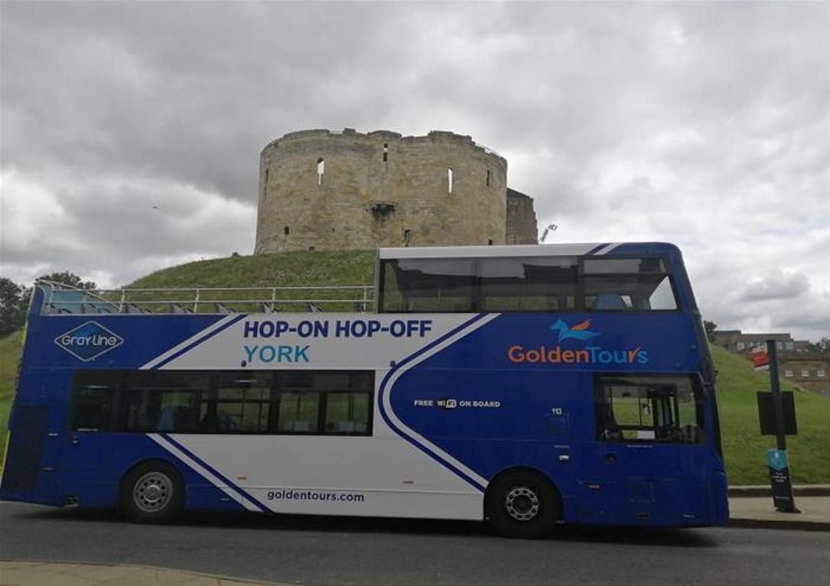 Un autobús de dos pisos estacionado frente a un castillo