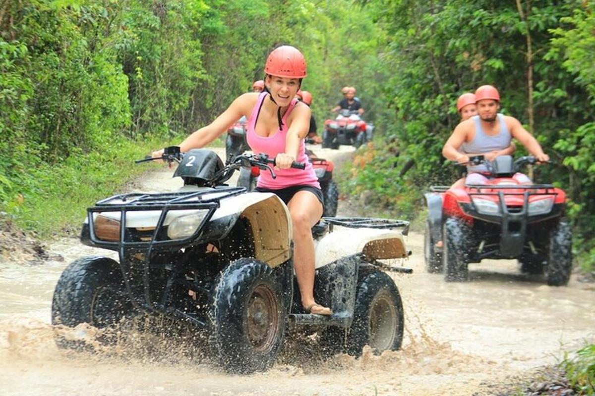 a group of people riding on four wheelers in the mud