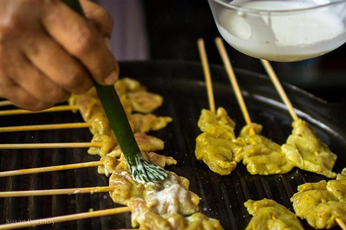 Una persona está cocinando comida en una parrilla con palillos.