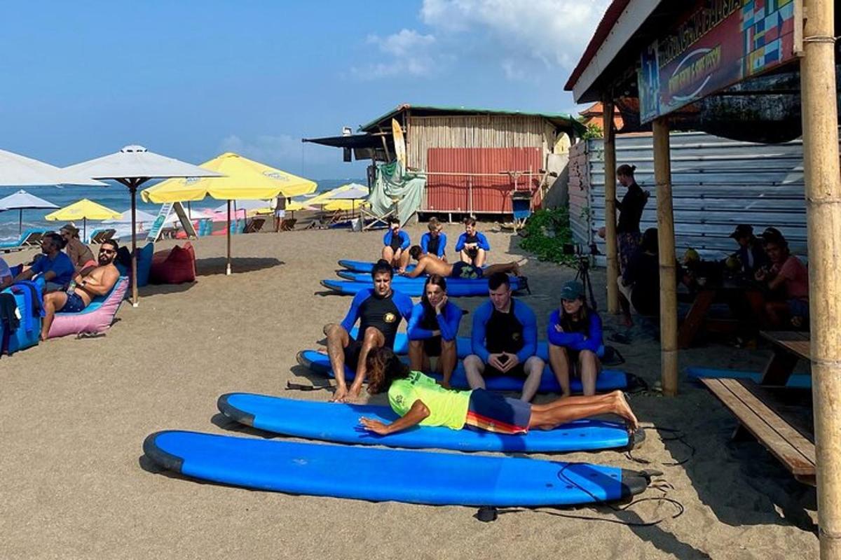 sekumpulan orang berbaring di atas papan luncur di pantai