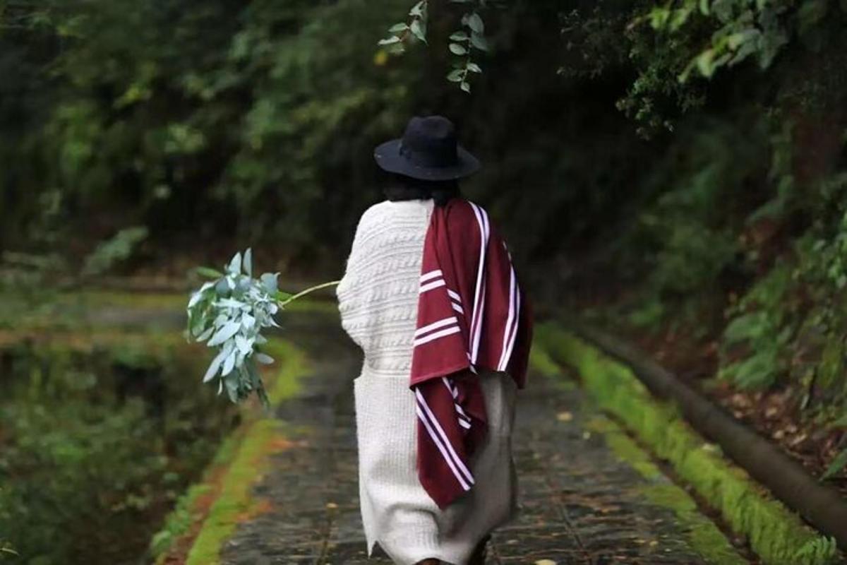 a woman in a hat walking down a path