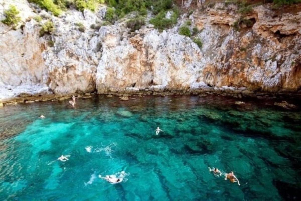 Μια ομάδα ανθρώπων που κολυμπούν στο νερό κοντά σε έναν απότομο βράχο