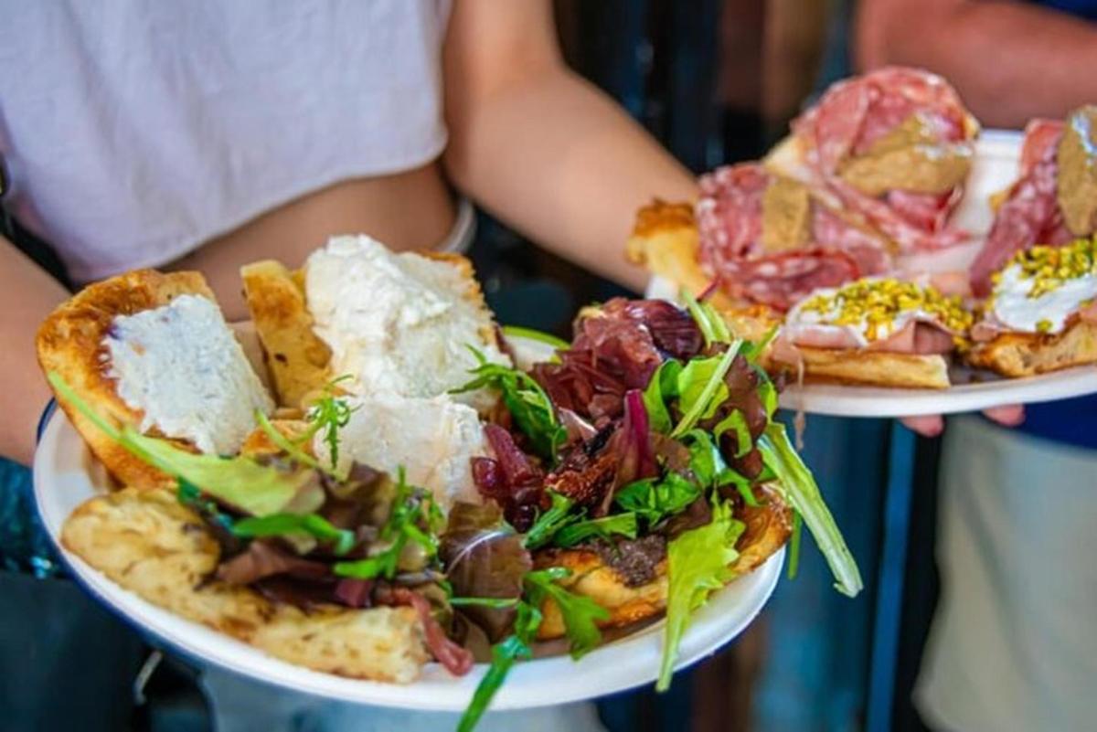 een persoon die twee borden met eten en pizza vasthoudt