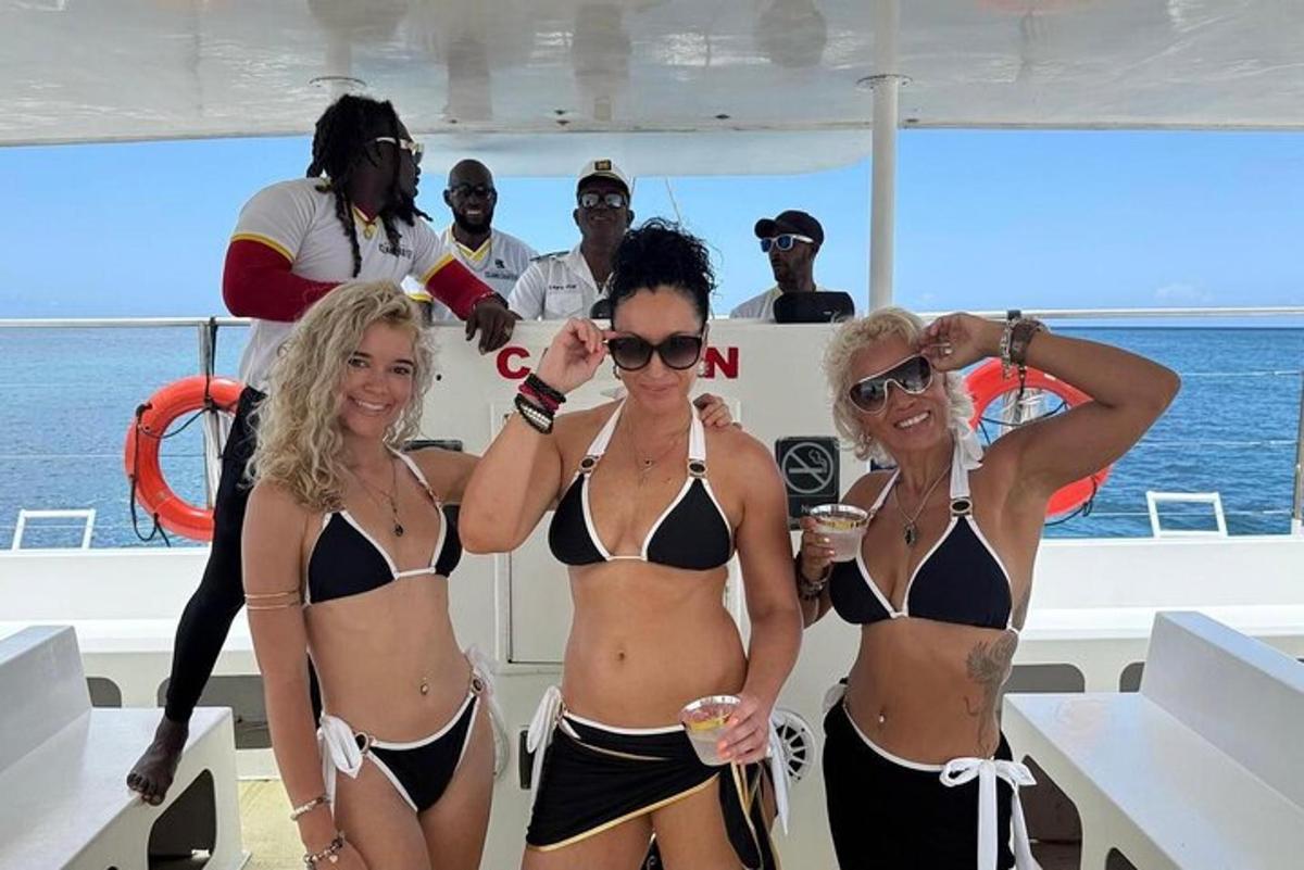 a group of women in bikinis standing on a boat