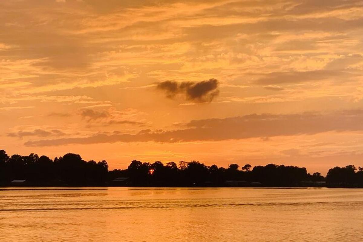 en solnedgang over en elv med trær i bakgrunnen