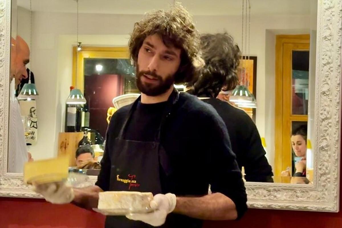 Un hombre con barba sosteniendo un trozo de queso