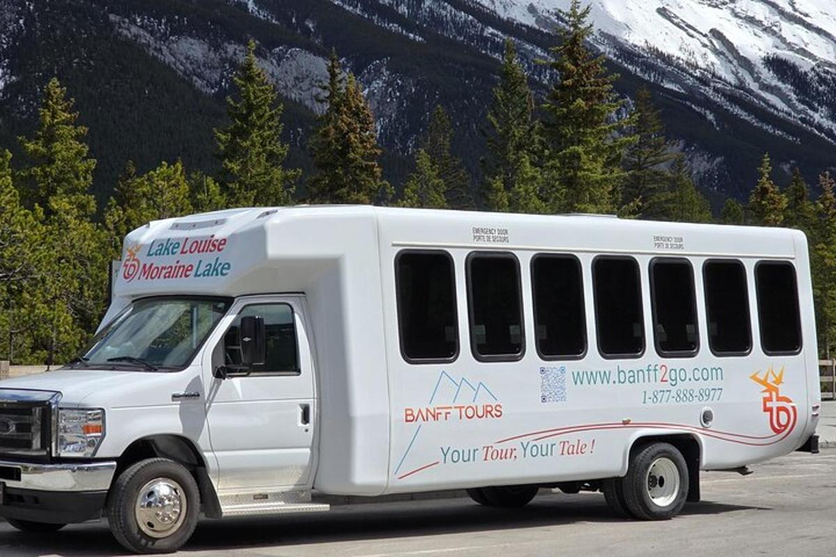 a white bus parked in a parking lot with a mountain