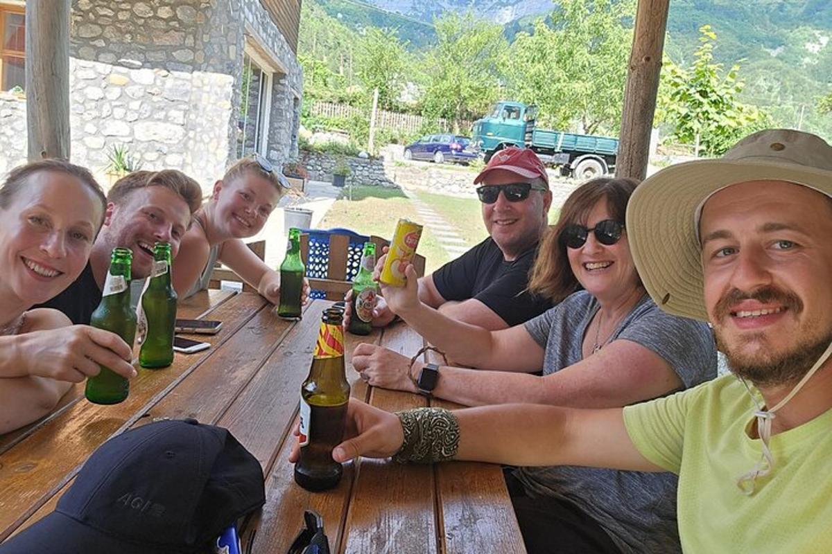 Un grupo de personas sentadas alrededor de una mesa de madera con botellas.