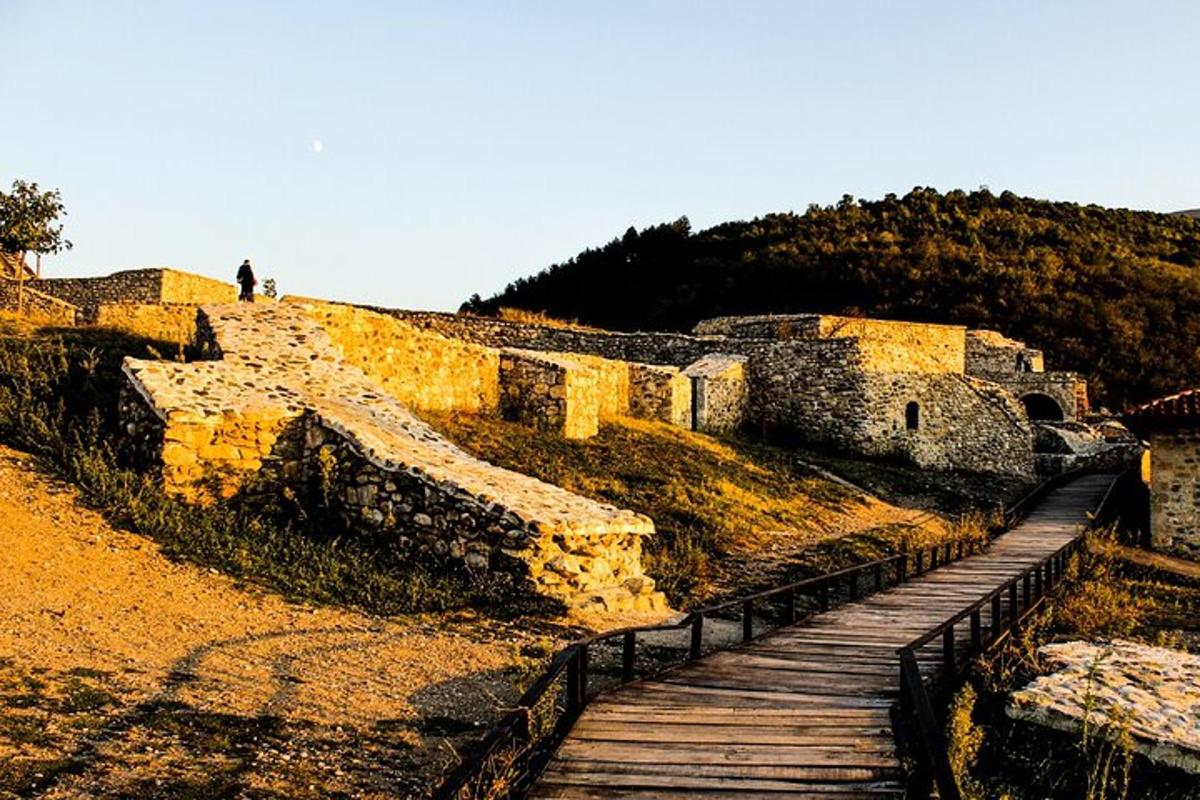žmogus eina mediniu takeliu šalia sienos