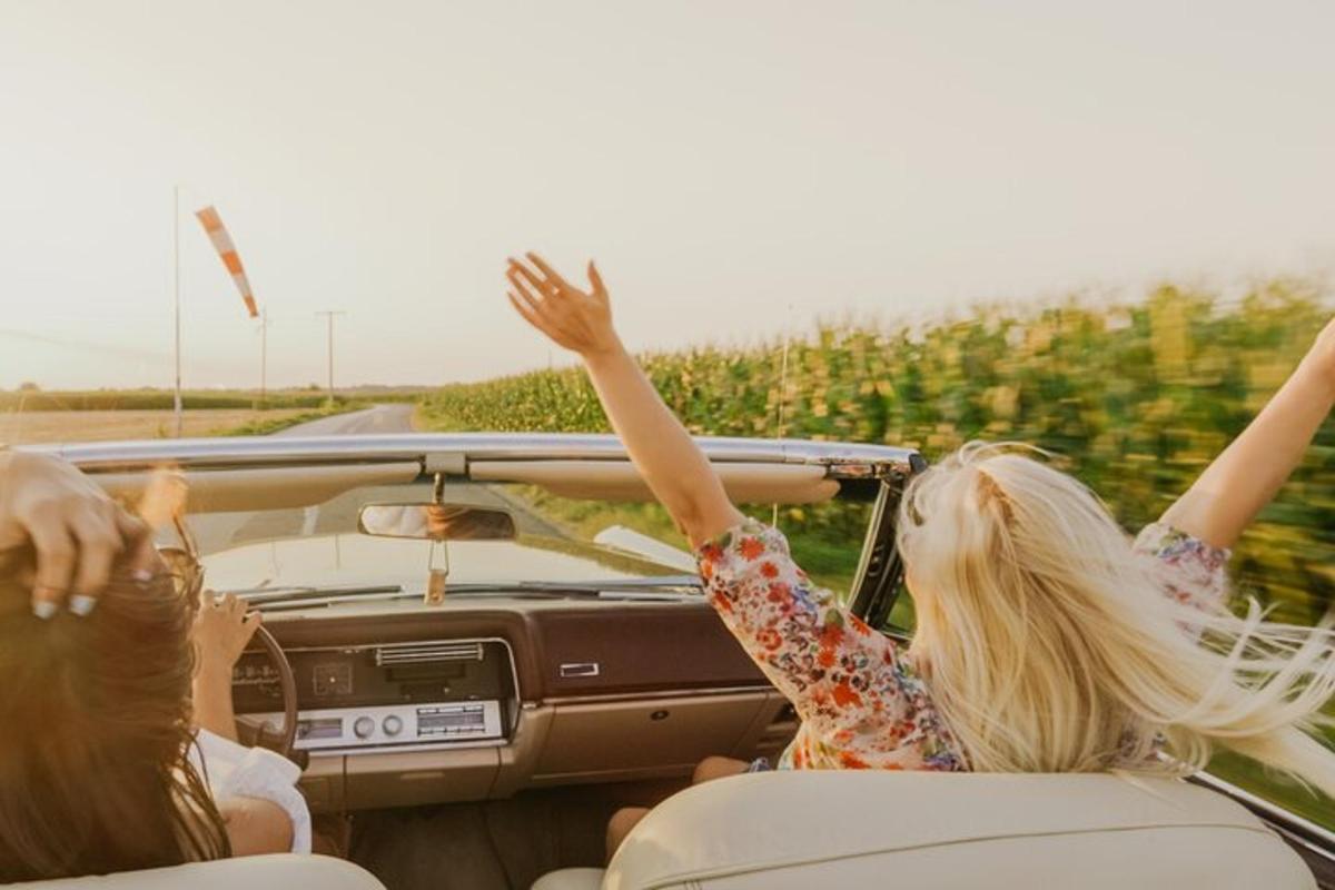 hai người phụ nữ trong một chiếc xe với hai tay giơ lên