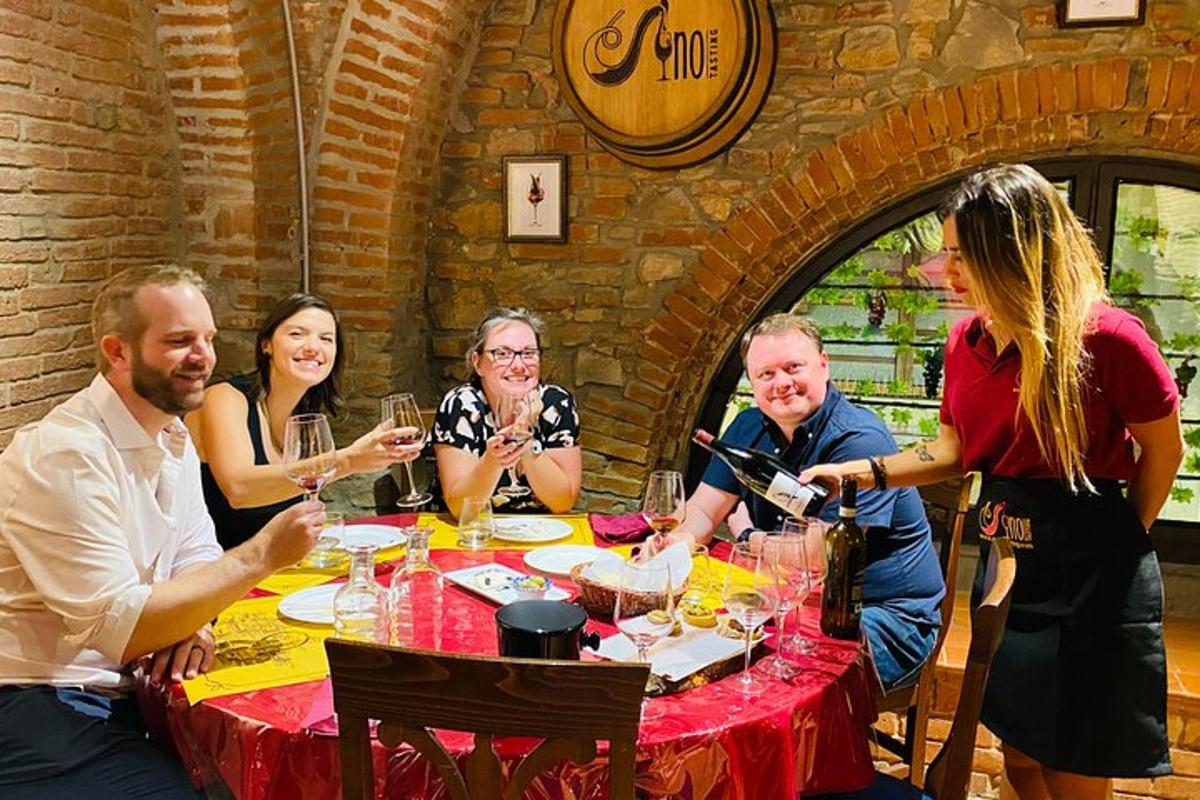 skupina lidí sedících kolem stolu a popíjejících víno
