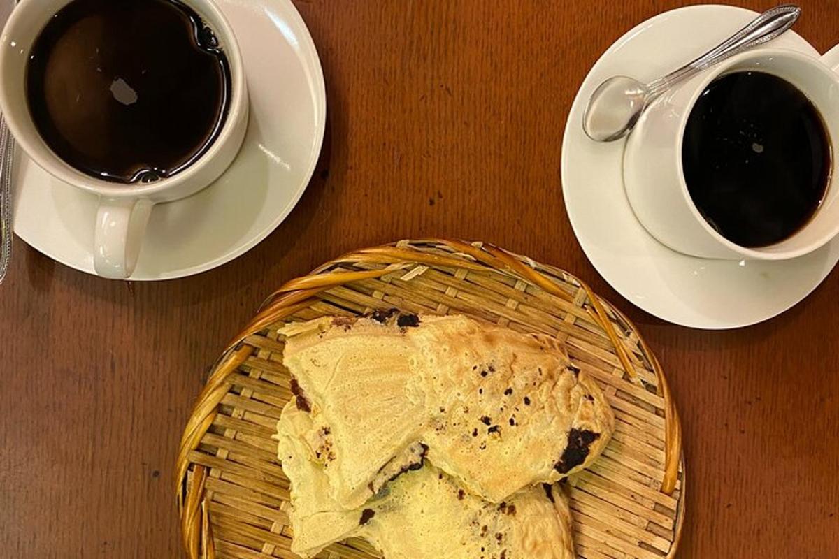 o masă cu o farfurie cu pâine și două cești de cafea