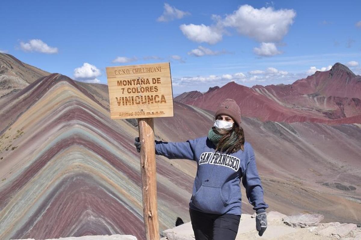 uma pessoa parada ao lado de uma placa em uma montanha