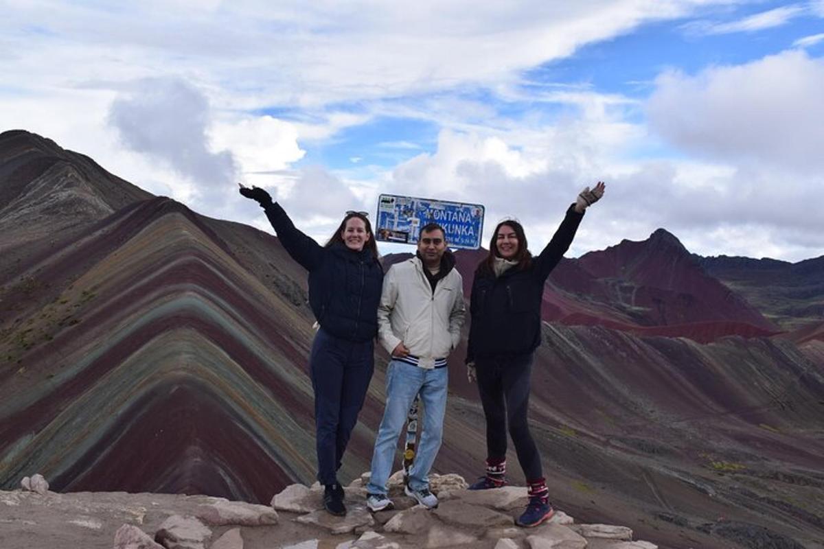 três pessoas em pé no topo de uma montanha