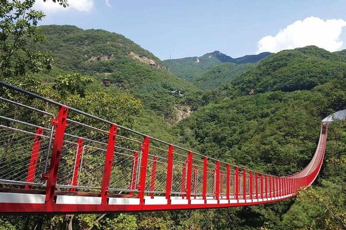 eine rote Hängebrücke über einem Bergtal
