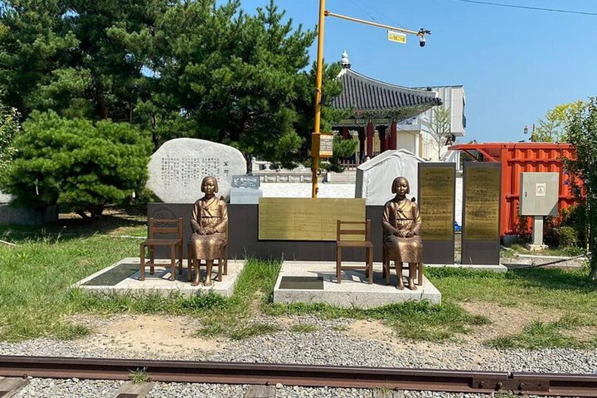dvě sochy mužů sedících na lavičkách na vlakovém nádraží