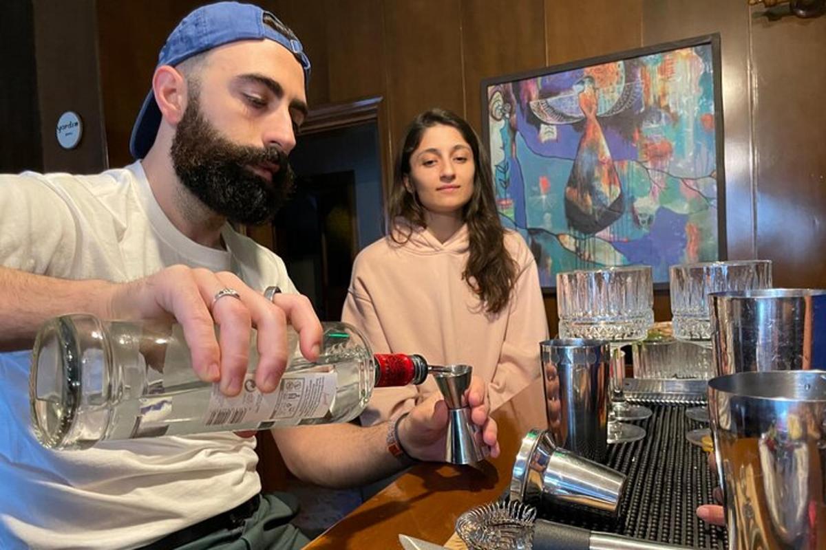 un bărbat toarnă o băutură dintr-o sticlă la o masă
