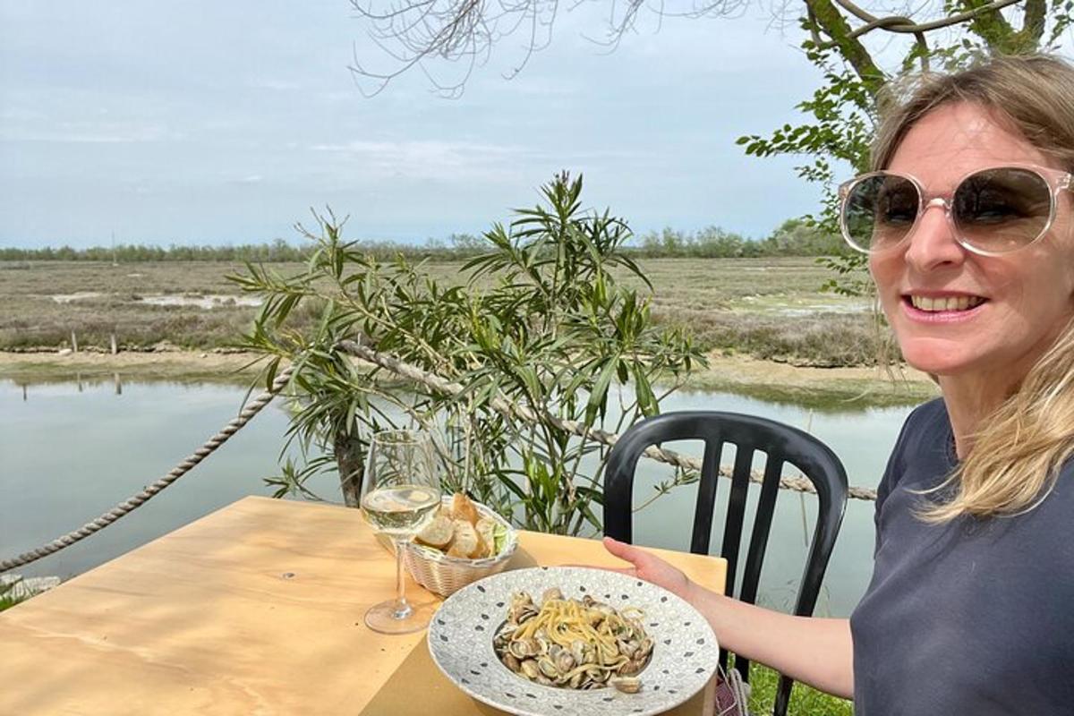 en kvinne som sitter ved et bord med en tallerken pasta
