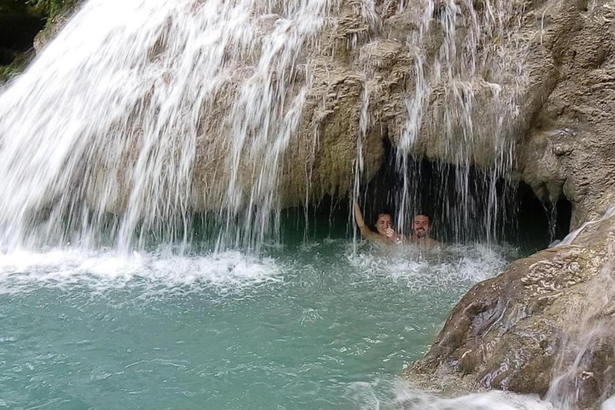 dva lidé v kaluži vody pod vodopádem