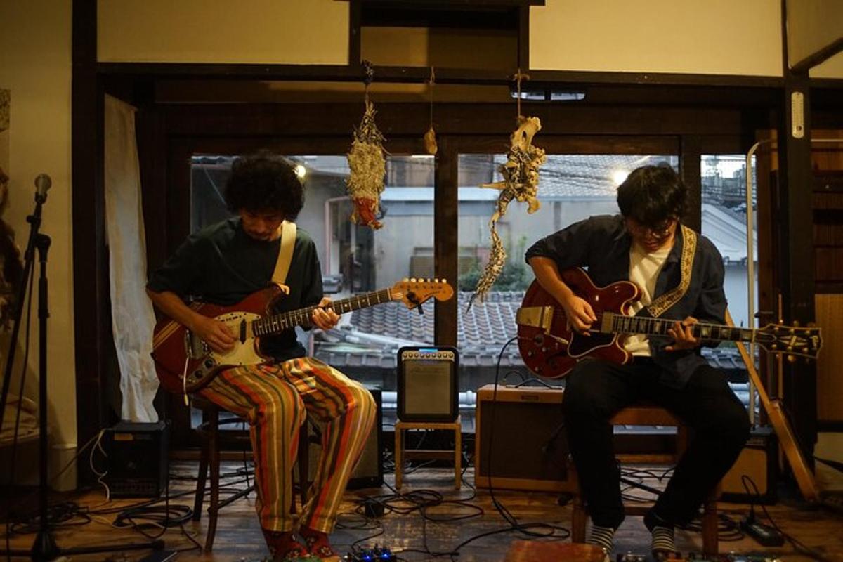 dois homens tocando suas guitarras em uma sala