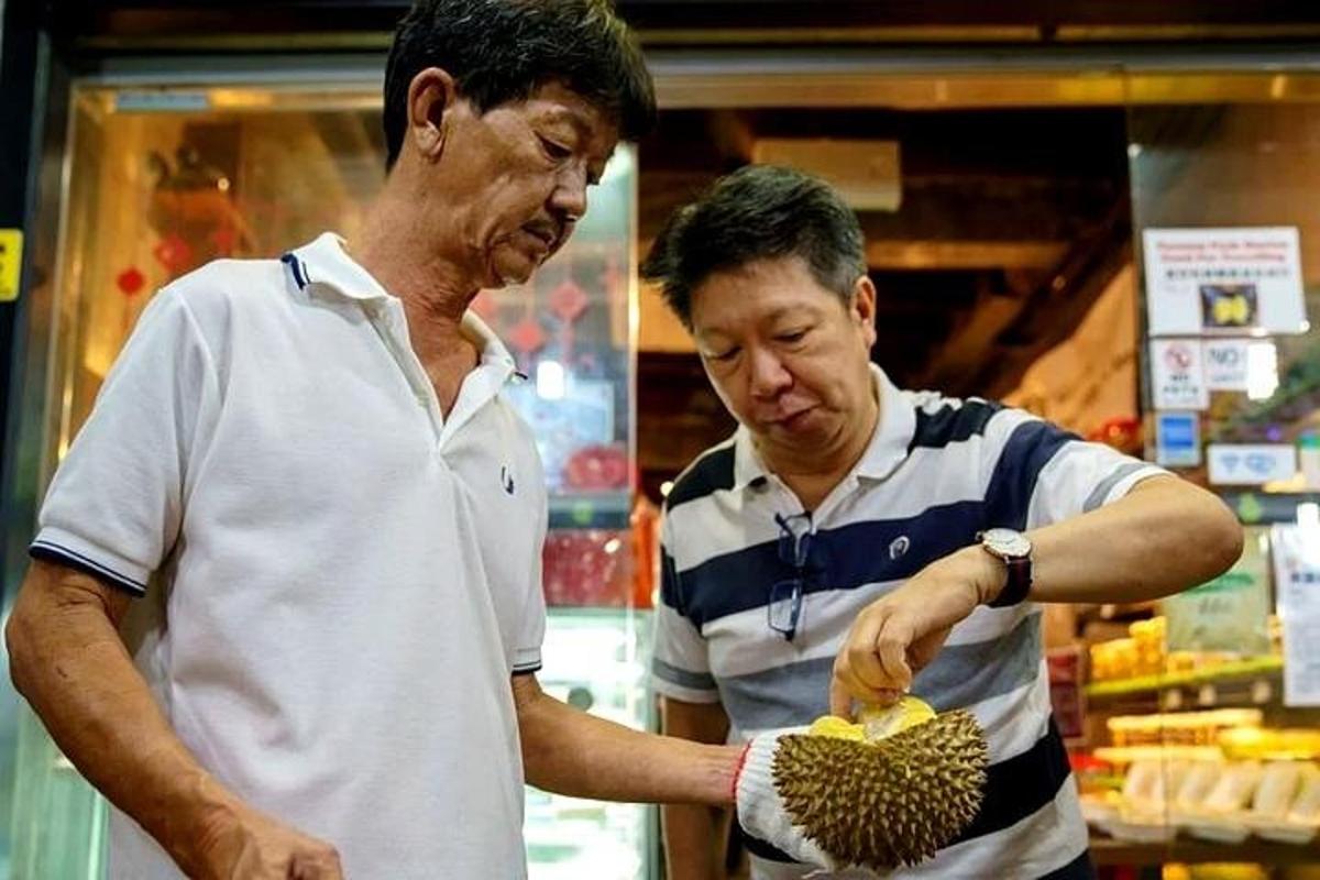 dva muži stojící v obchodě a prohlížející si durian