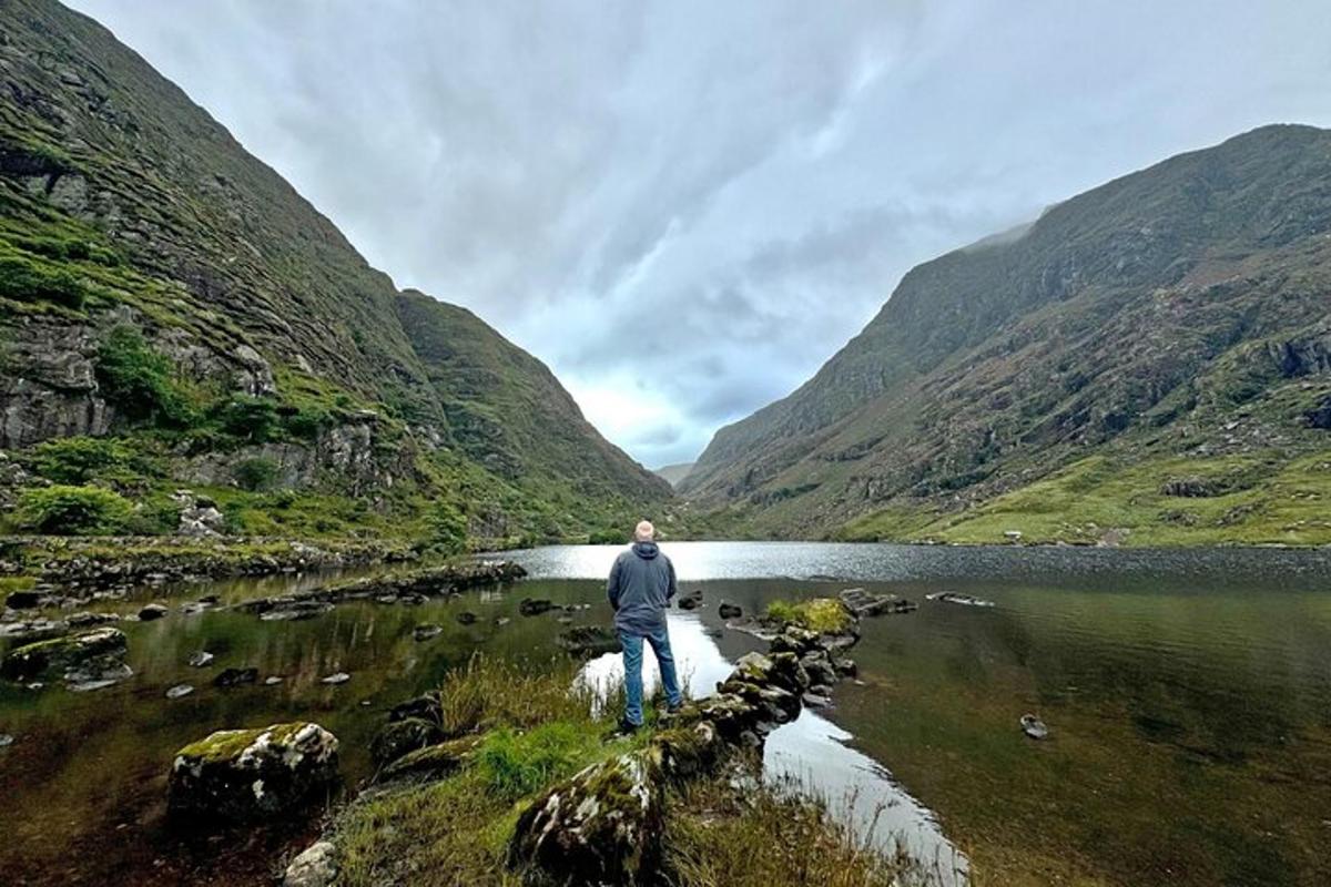 Un hombre parado sobre una roca en un lago de montaña