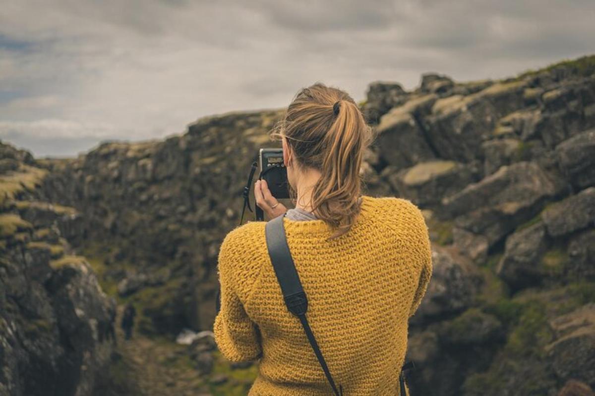 Una mujer tomando una foto de una montaña con su teléfono celular.