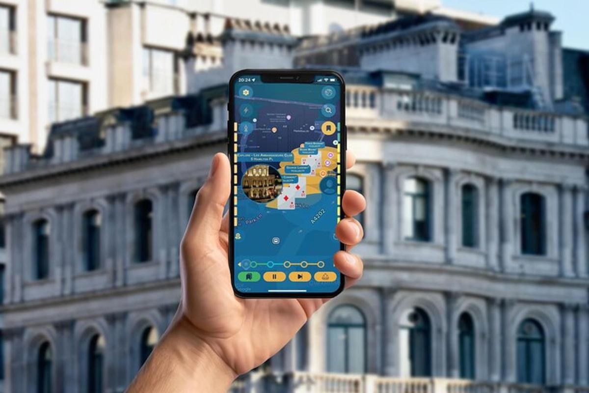 ruka držící mobilní telefon před budovou
