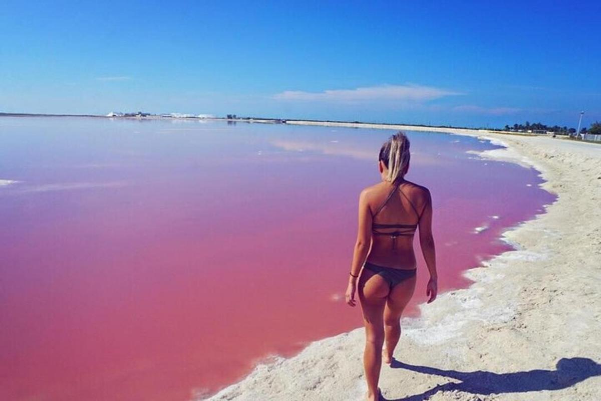 una mujer caminando por la playa con agua rosada