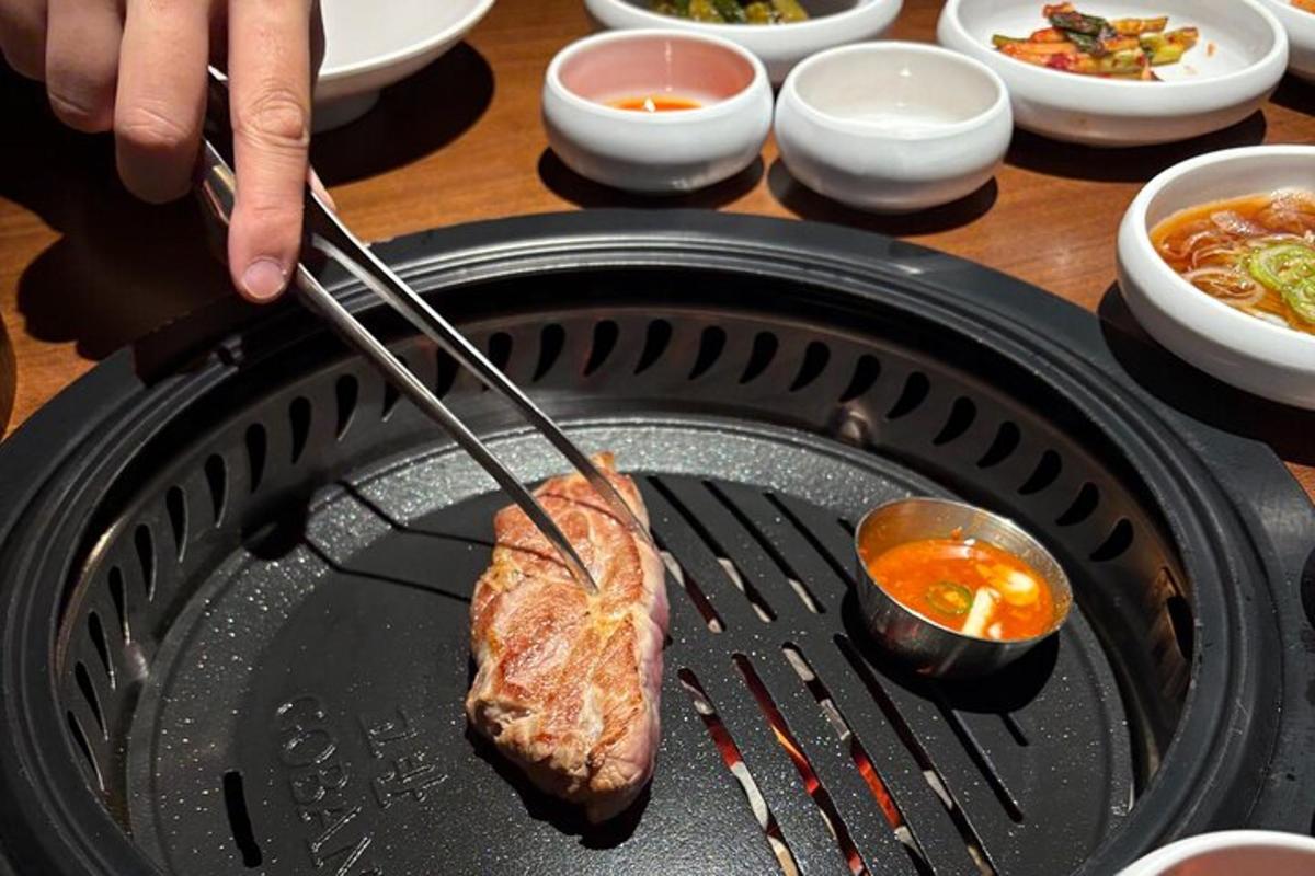 eine Person kocht ein Stück Fleisch auf einem Grill