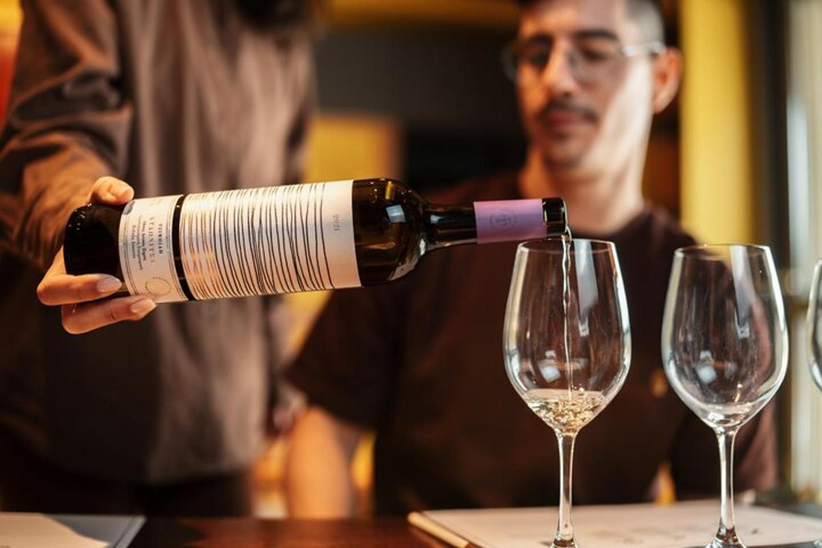 moški, ki naliva steklenico vina v dva kozarca za vino