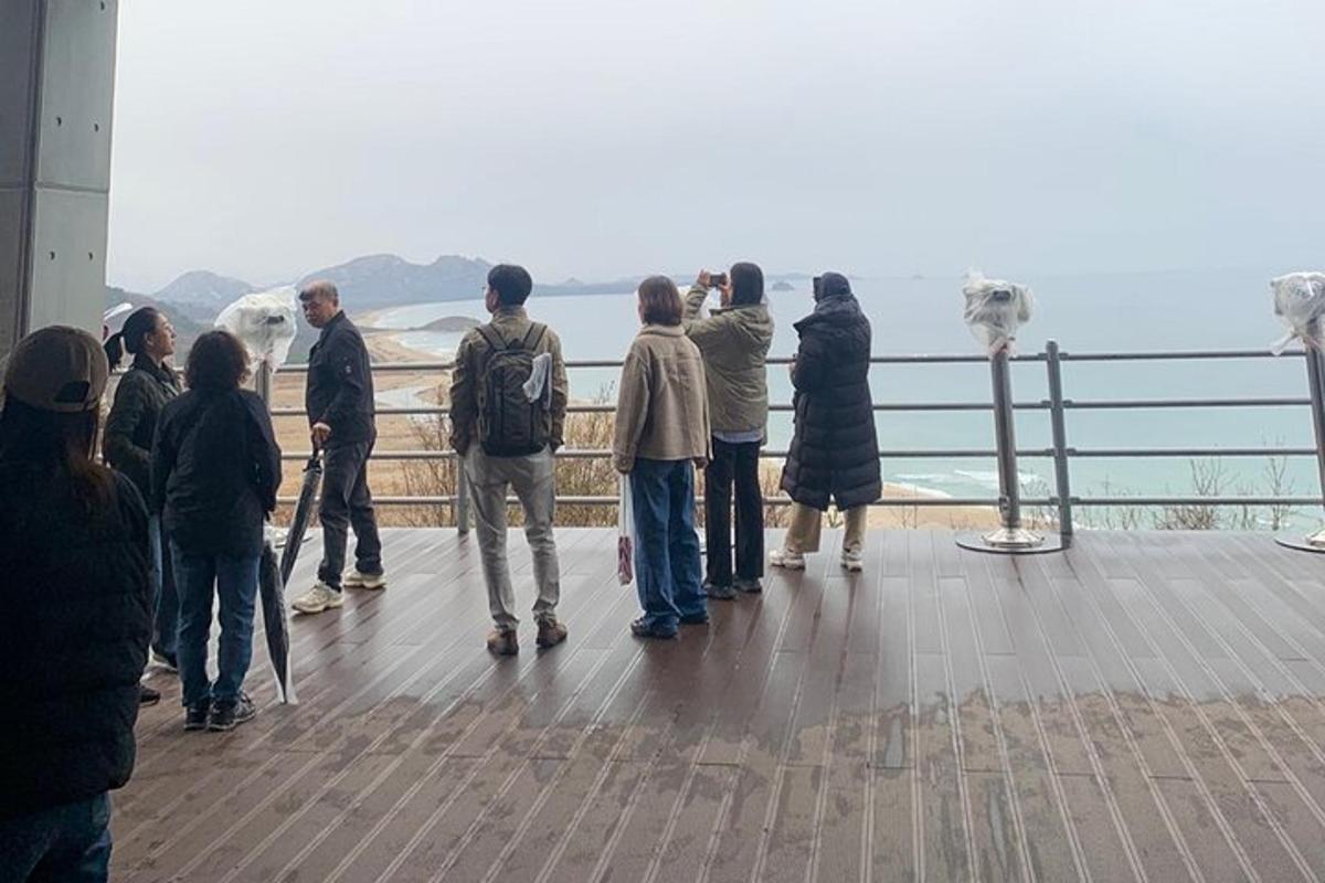 a group of people standing on a viewing deck looking at the ocean