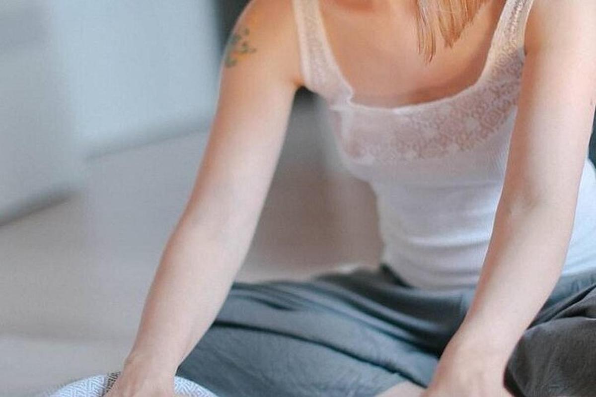 uma jovem sentada na cama com o braço