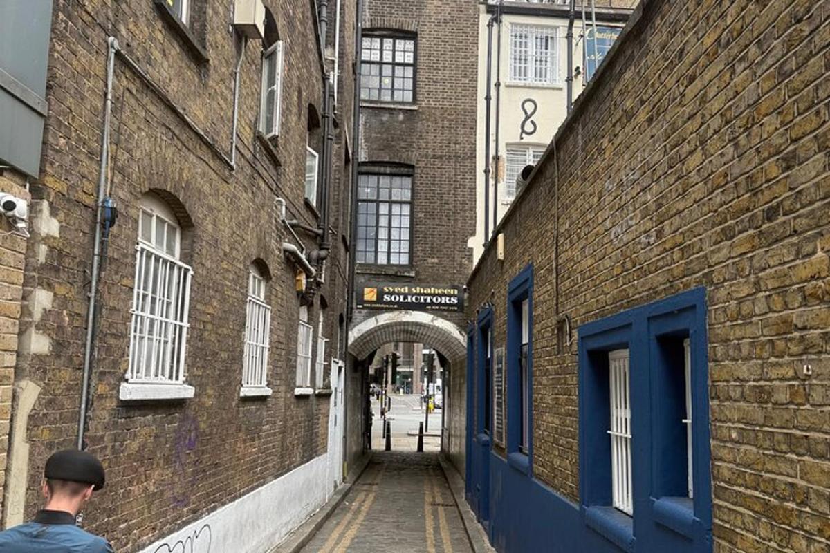 a man walking down an alleyway between two brick buildings