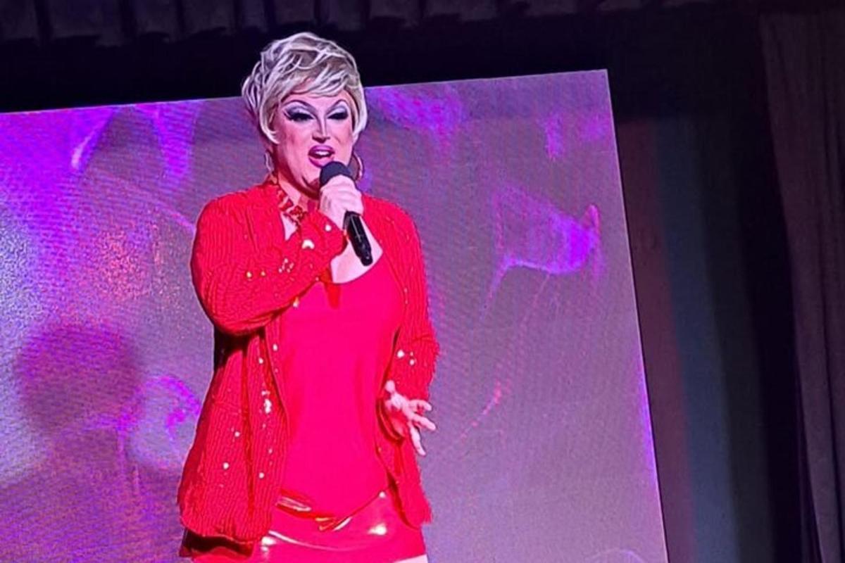 seorang wanita berdiri di atas pentas memegang mikrofon
