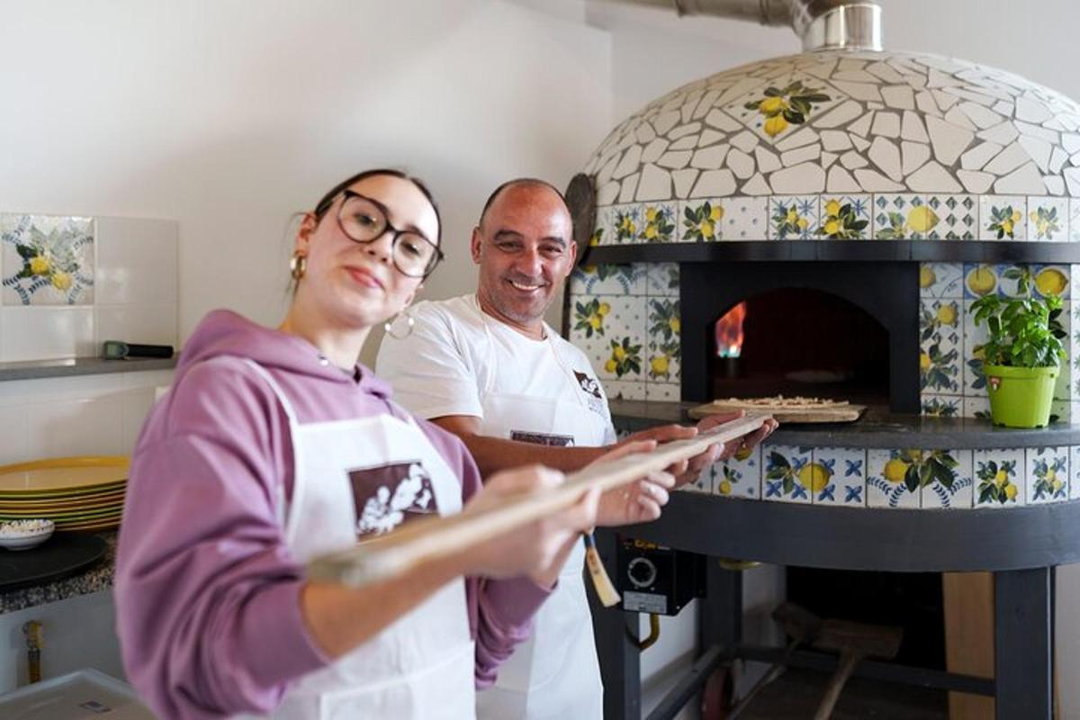 un bărbat și o femeie stând în fața unui cuptor de pizza